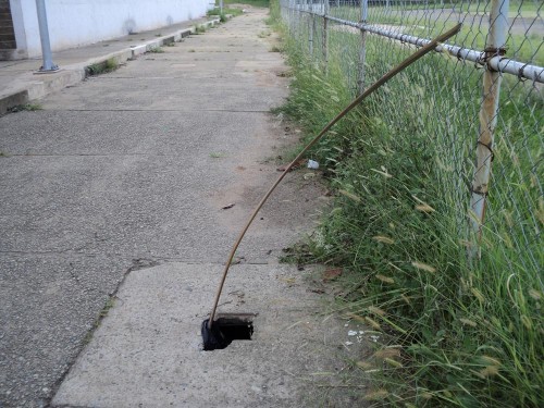 Piso ao lado da pista de atletismo tem buraco sinalizado com pedaço de madeira