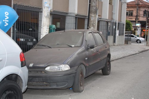 O Carro Fiat, modelo Palio, está abandonado em uma das ruas mais movimentadas do bairro